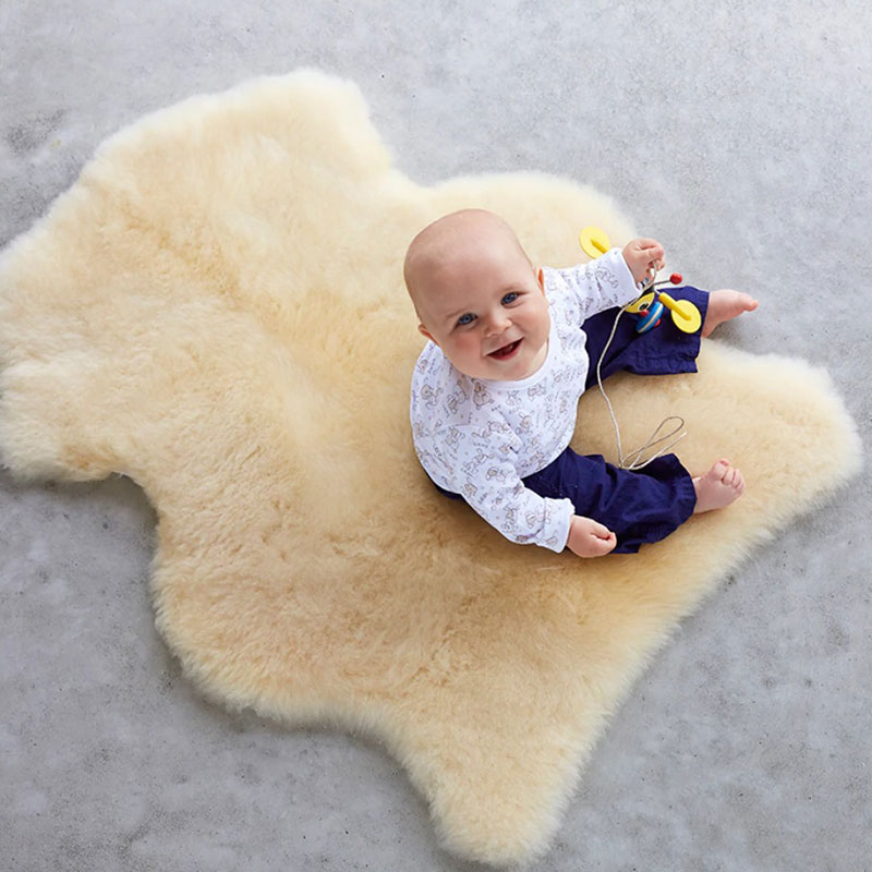 Infant sitting on sheepskin rug