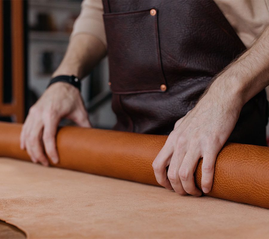 Craftsmen rolling out leather